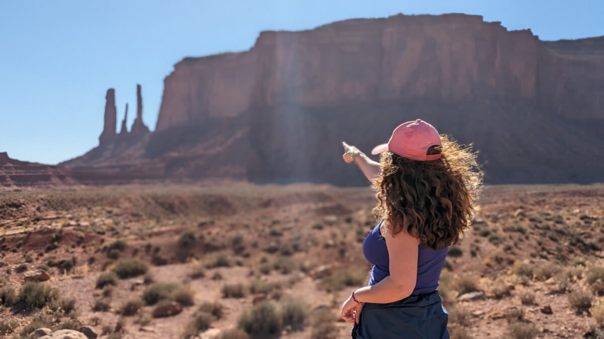 Une jeune femme de dos montre du doigt les Three Sisters