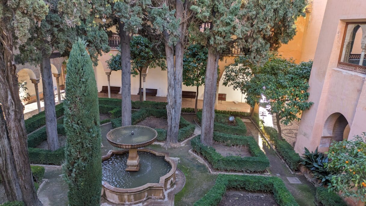 Un jardin avec une fontaine, et quelques orangers.